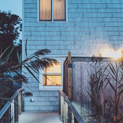 A close-up of a house at dusk with the lights on